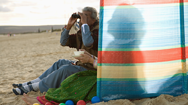 women on beach behind windbreak