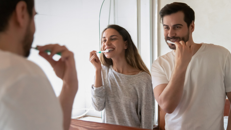 Woman and man brushing their teeth