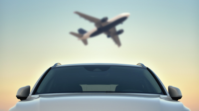 Parked car at sunset under departing airplane