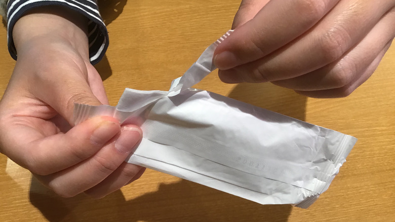 Person opening disposable oshibori wrapper