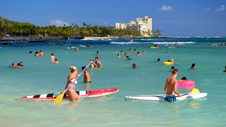 People swimming and paddleboarding on Waikiki Beach in Hawaii