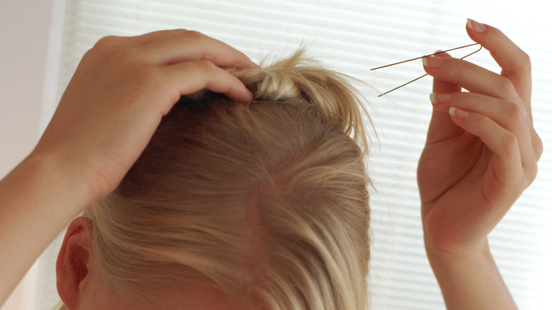 woman adjusting hairdo with hairpin
