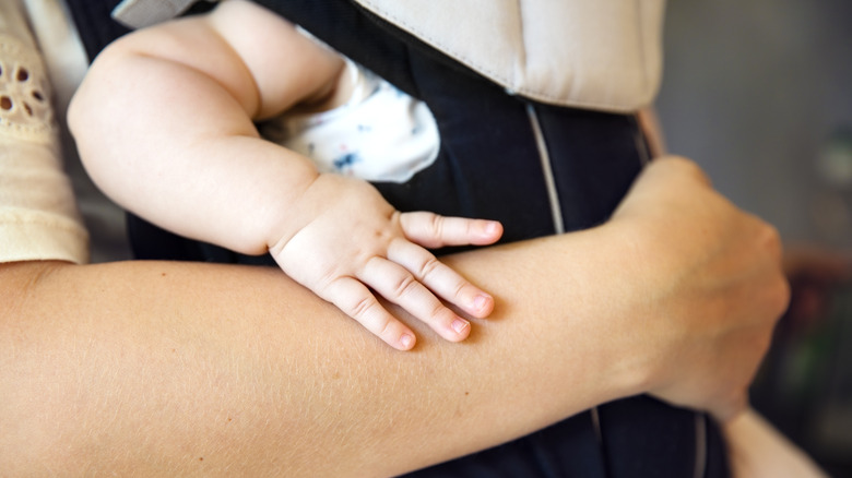 parent holding baby in carrier