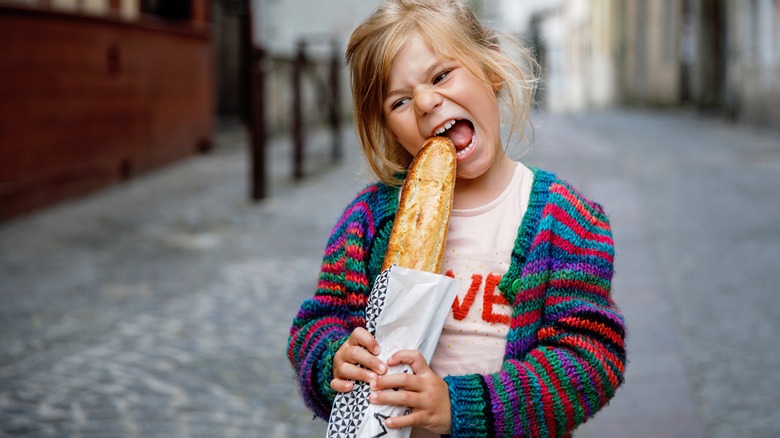 Young girl biting baguette