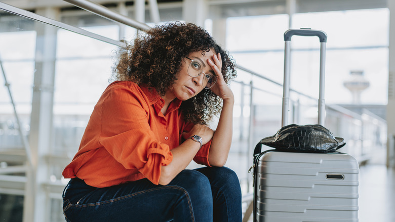 Sad woman at airport sitting on the floor