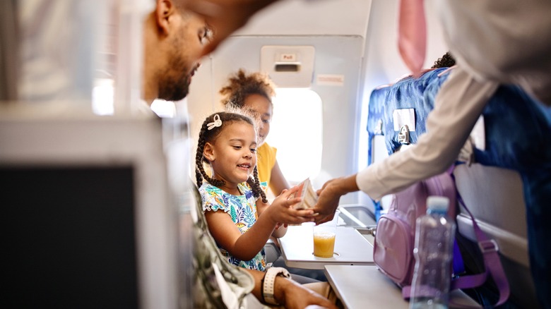 Flight attendant serving a child passenger