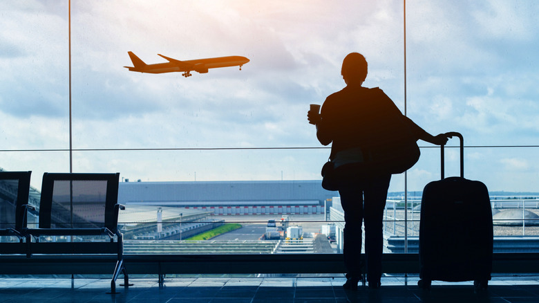 A woman watches an airplane take off