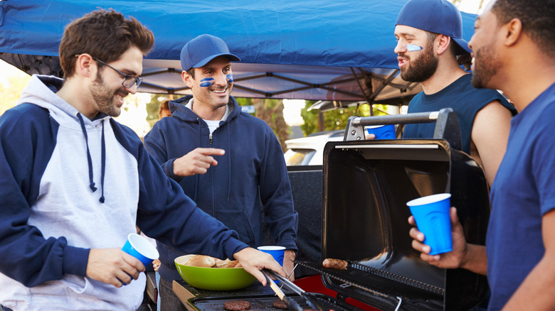 four men near grill while tailgating