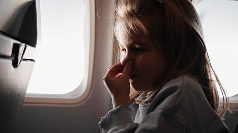 Girl on airplane holding her nose