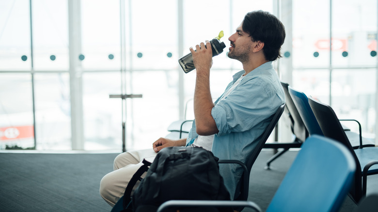 man at airport drinking water
