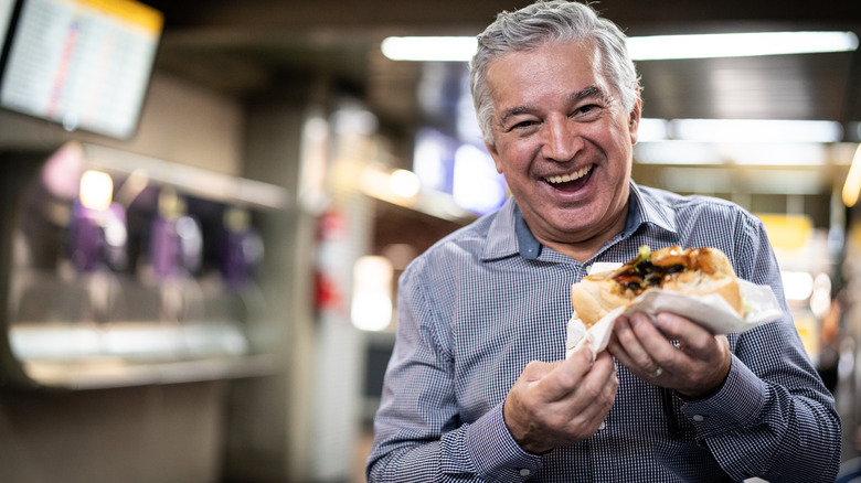 Smiling traveler eating a sandwich