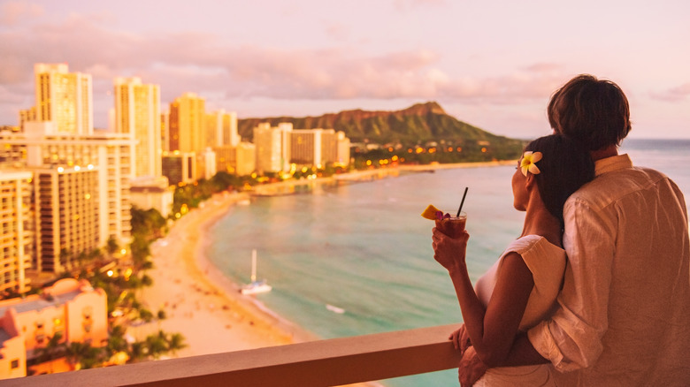 Couple look at Waikiki beach from balcony 