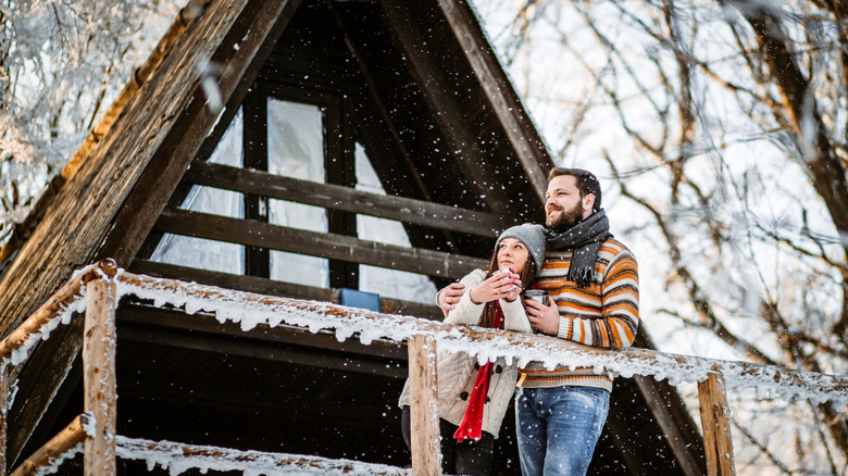 couple on snowy cabin porch