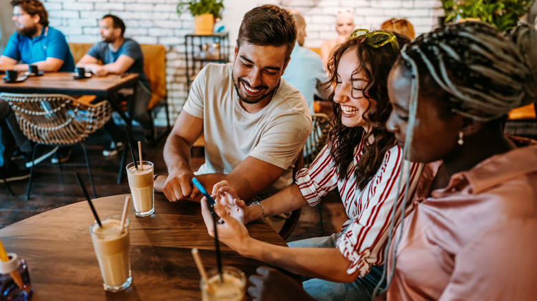 friends using phone in restaurant