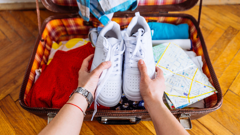 Person holding shoes over suitcase