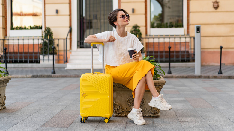 Woman with suitcase sitting on European street