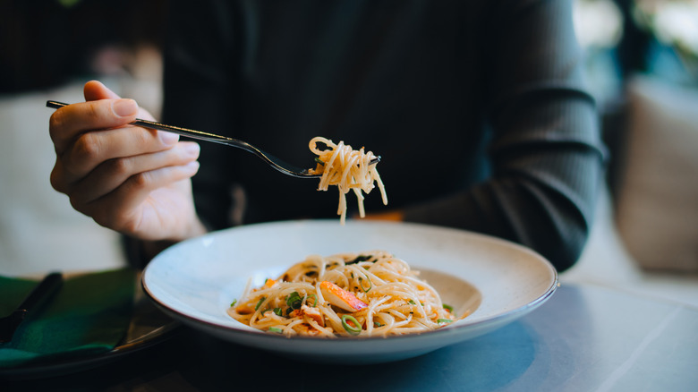 person eating spaghetti in restaurant