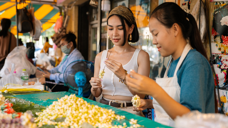 Tourist making a floral garland in Thailand