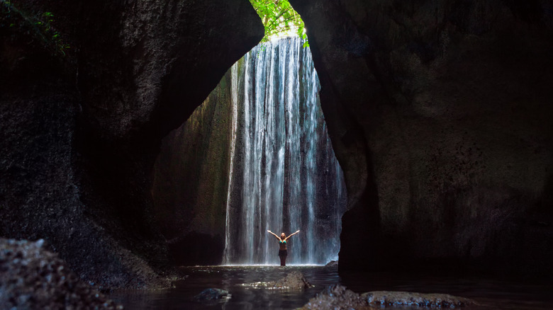 Woman standing under waterfall