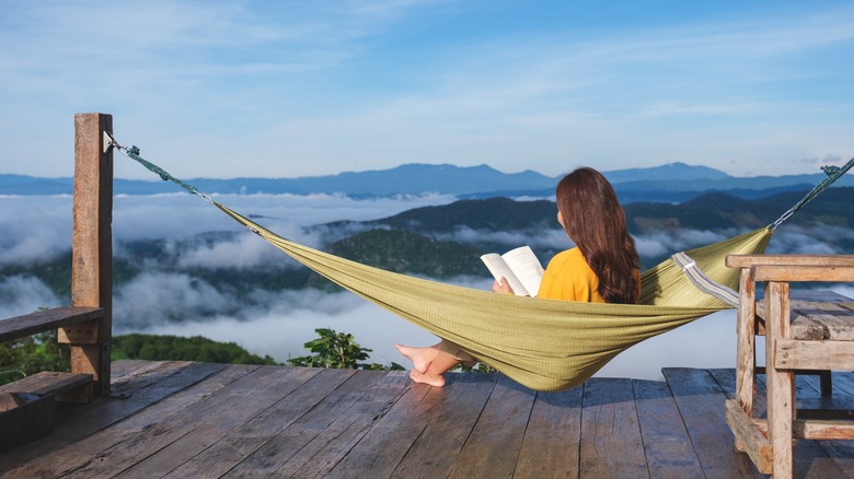 Woman reading a book in hammock with mountain view