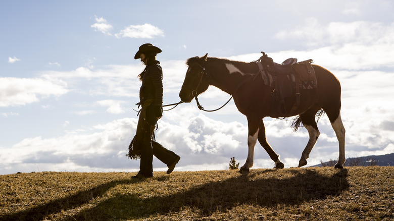 Woman walking with horse along ridge