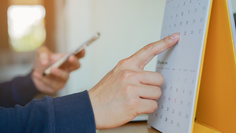 Finger pointing to a date on a calendar