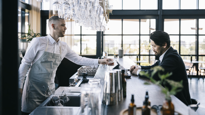 Waiter serving traveler at bar