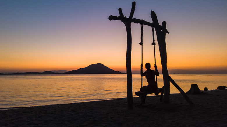 Person on swing at sunset