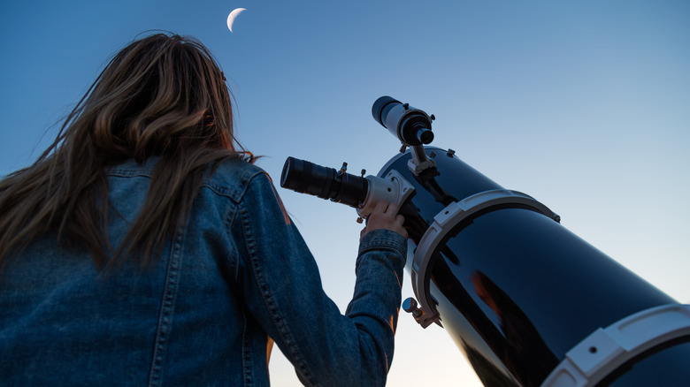 Woman looking up with a telescope