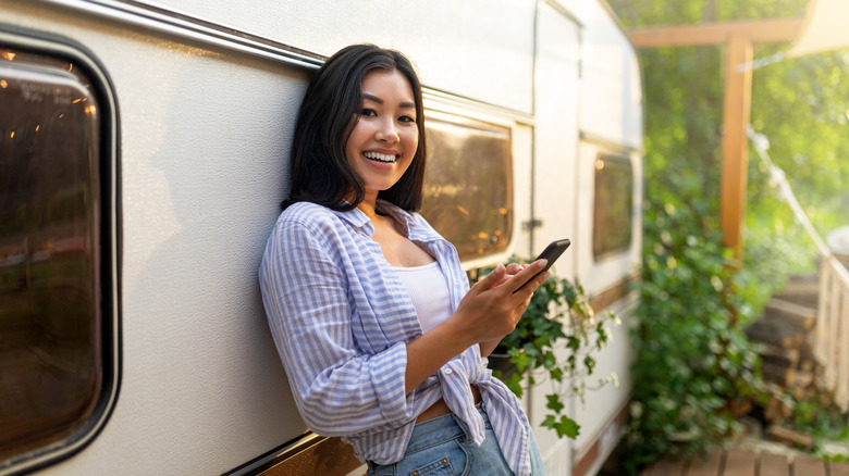 Happy woman using her phone by her RV