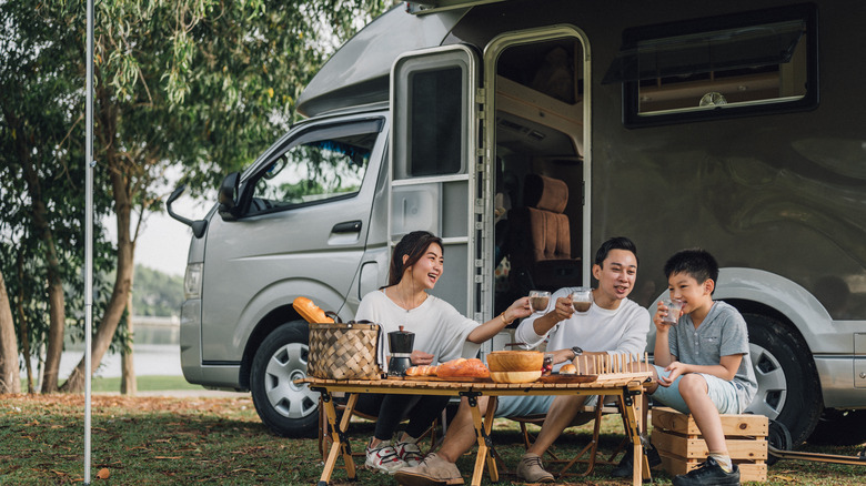 Family drinking coffee outside RV