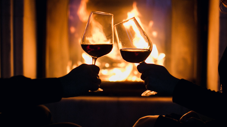 Wine glasses clinking by fire