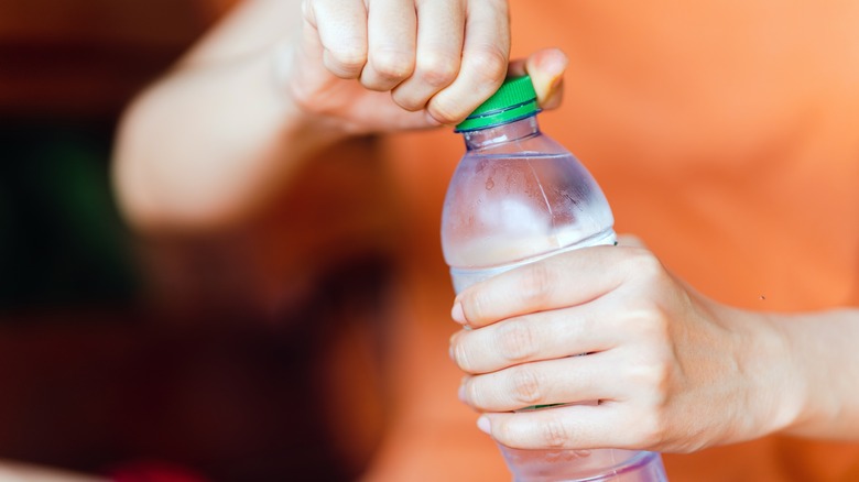 Hands opening a plastic water bottle