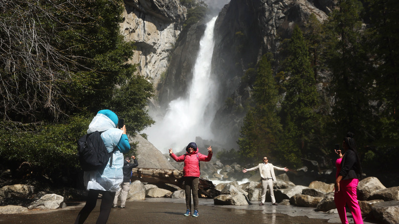 People taking pictures in front of waterfall