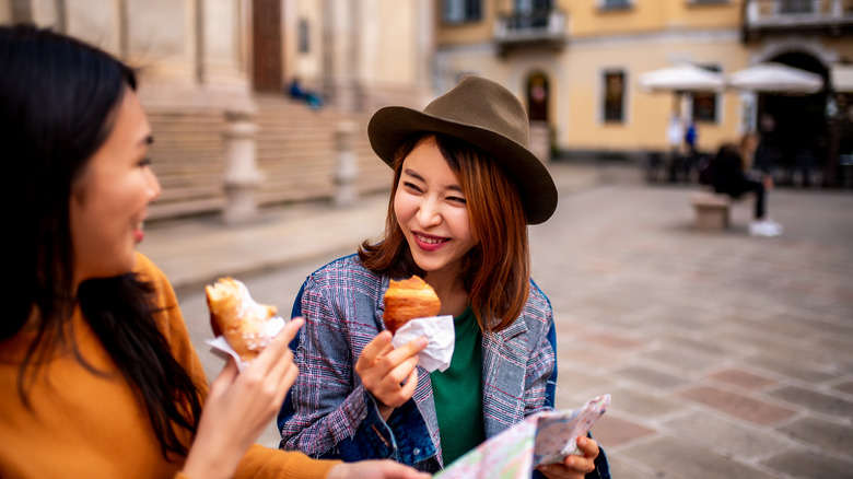 Two women eating pastries