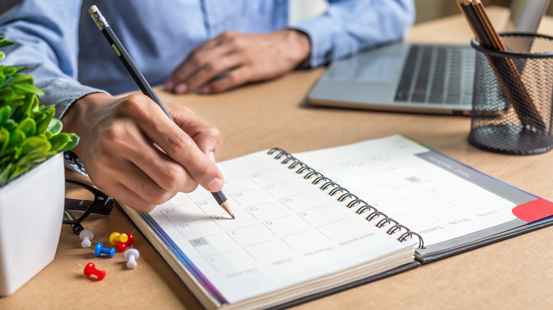 man writing in a calendar