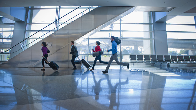 Four people running with their luggage in the airport