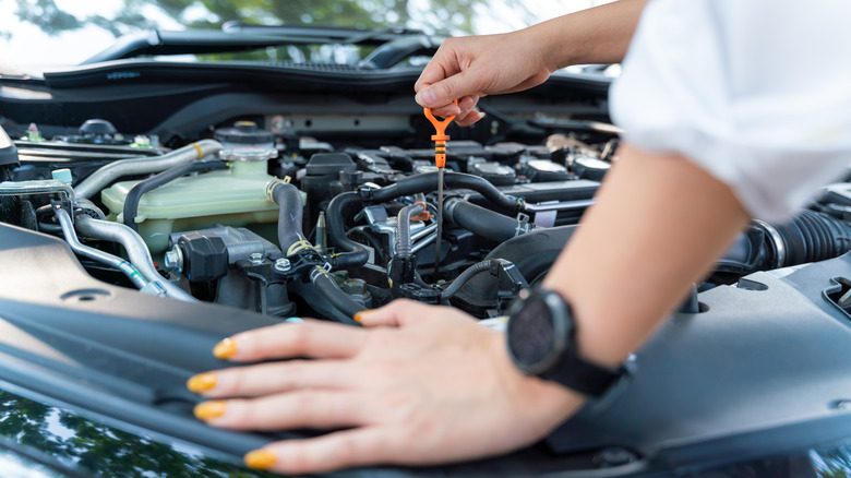 woman checking oil in car