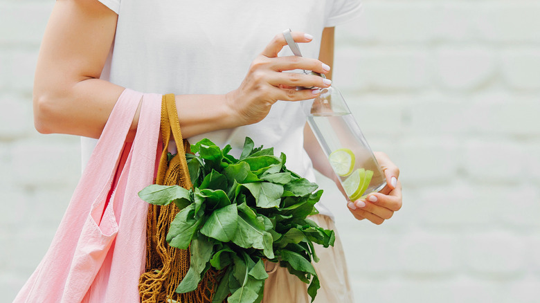 Woman carrying glass water bottle