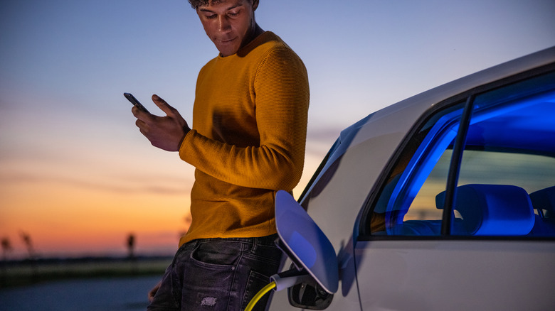 A man charging his car at sunset