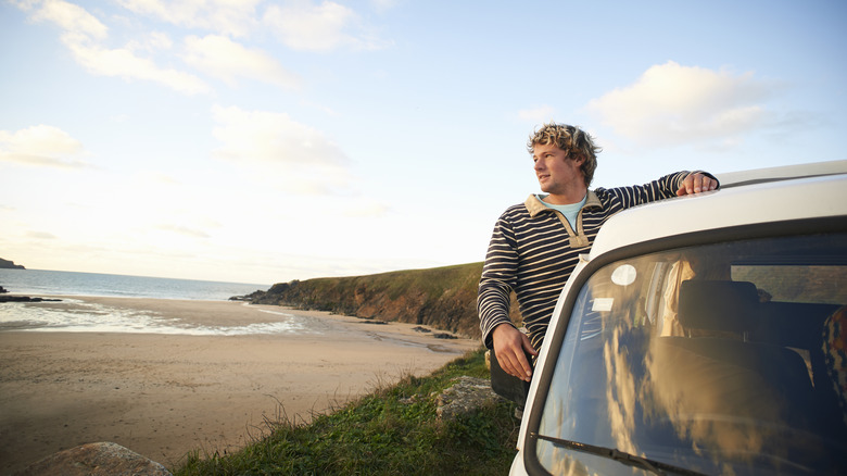 A young man looks out to the beach from his van