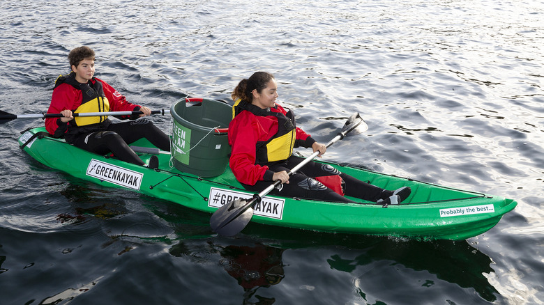 Two kayakers with a garbage bin in their boat in Copenhagen.