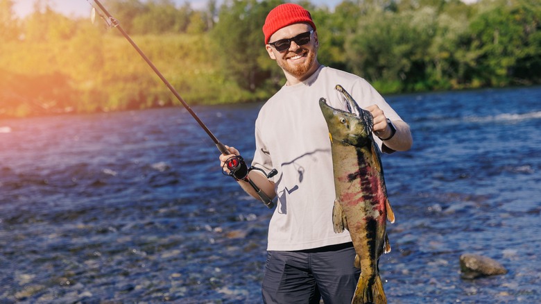 man holding a salmon and fishing rod