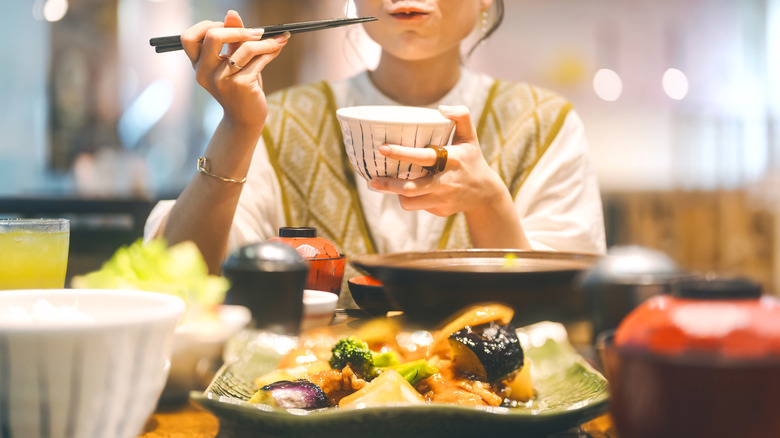 A woman eats with chopsticks.