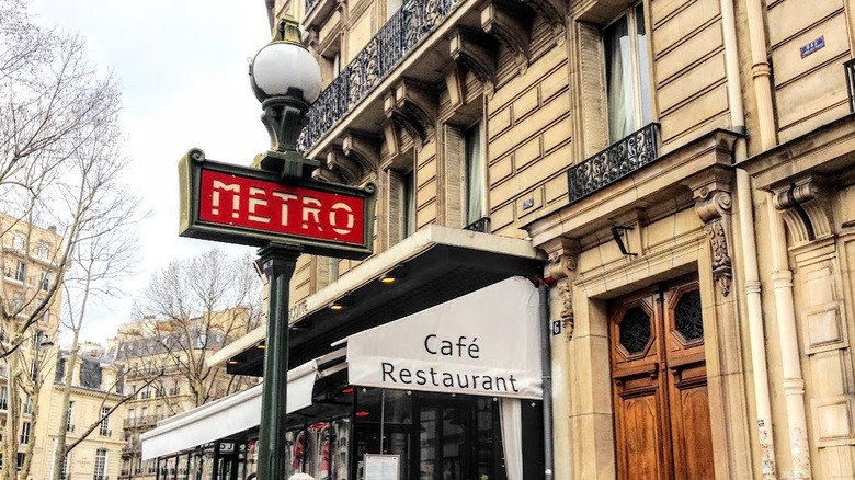 A metro sign near a cafe in Paris.