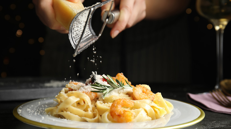Grating cheese over seafood pasta