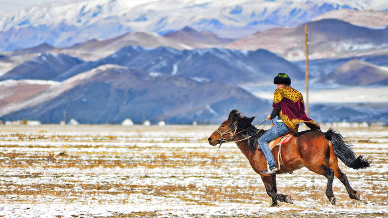 Man on a horse in snow dusted plains