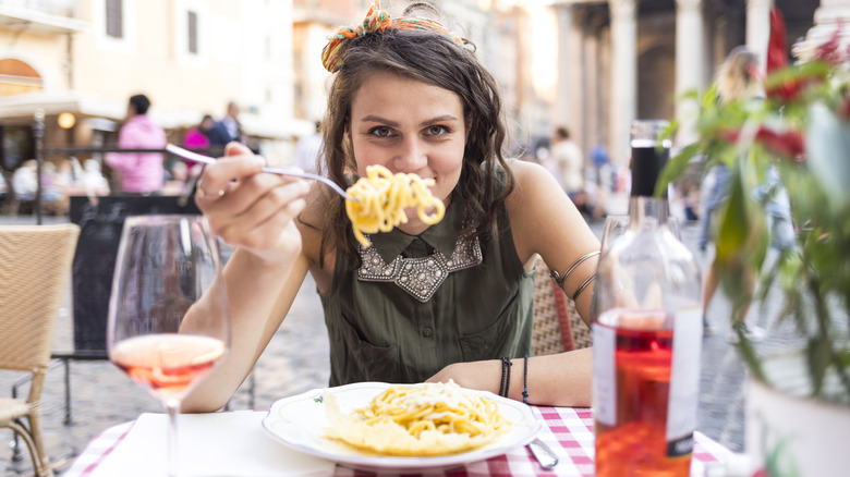 Traveler holding out forkful of spaghetti