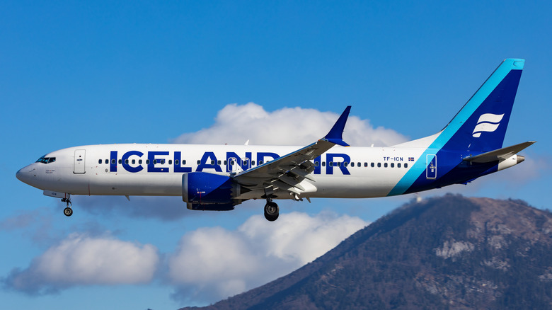 Icelandair plane flying past mountain and clouds