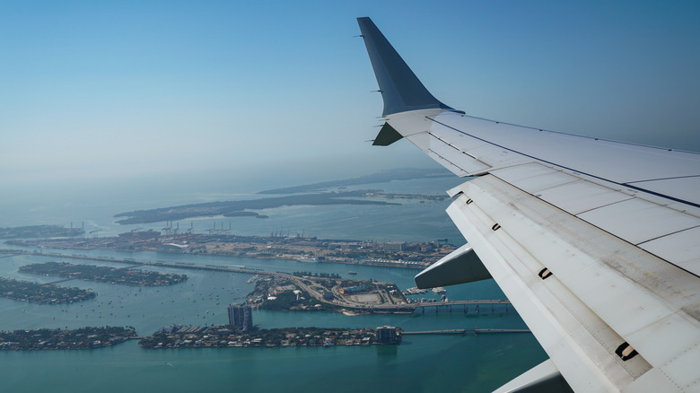 view from plane window of plane wing flying above Miami International Airport